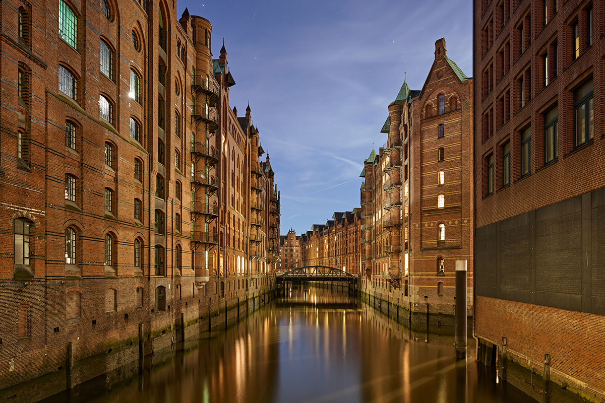 Abendliche Aufnahme der beleuchteten Hamburger Speicherstadt mit Kanal und historischen Backsteingebäuden