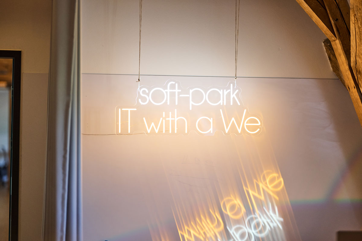 Leuchtschrift „soft-park – IT with a We" an der Wand im Büro