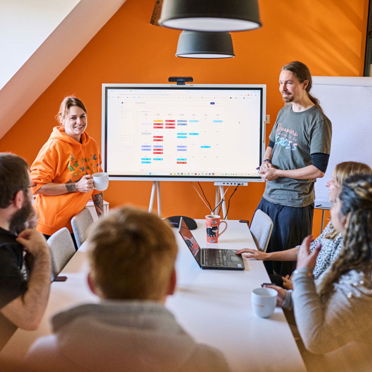 Das soft-park-Team bespricht ein Projekt im Meetingraum vor einem großen Bildschirm mit einem bunten Planungsdiagramm