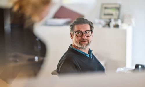 Blick durch eine Glasscheibe auf einen soft-park-Mitarbeiter im Gespräch mit einer Kollegin